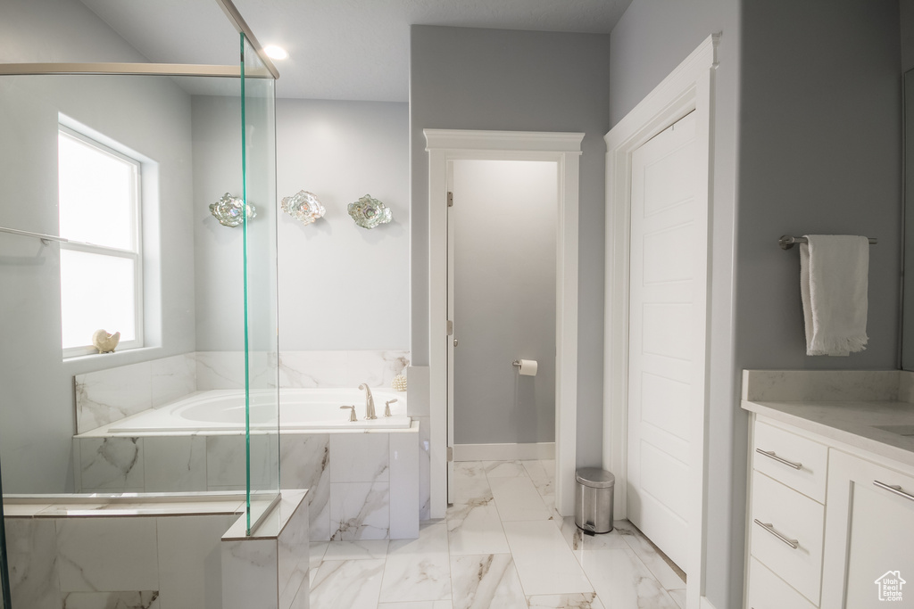 Full bathroom with marble finish floor, baseboards, a garden tub, and vanity