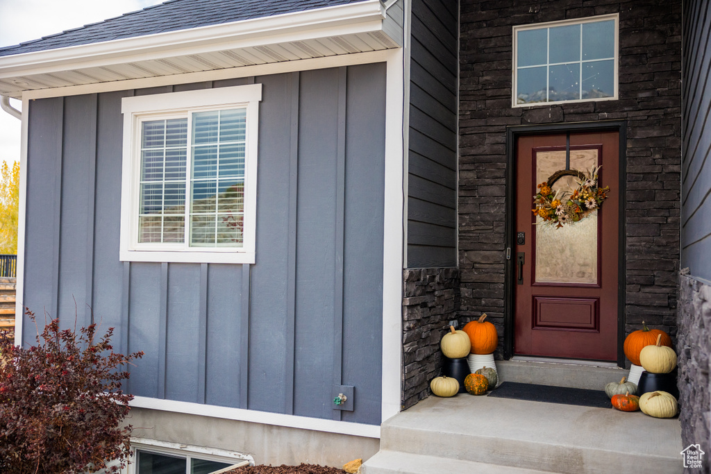Entrance to property with a shingled roof and board and batten siding