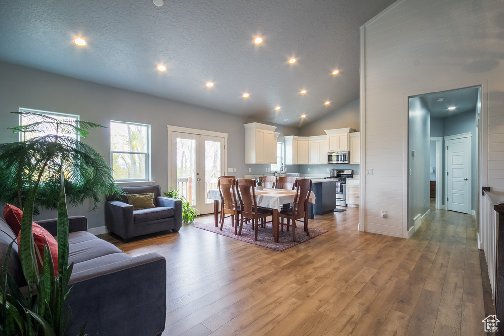 Dining room with french doors, high vaulted ceiling, baseboards, recessed lighting, and light wood-style flooring