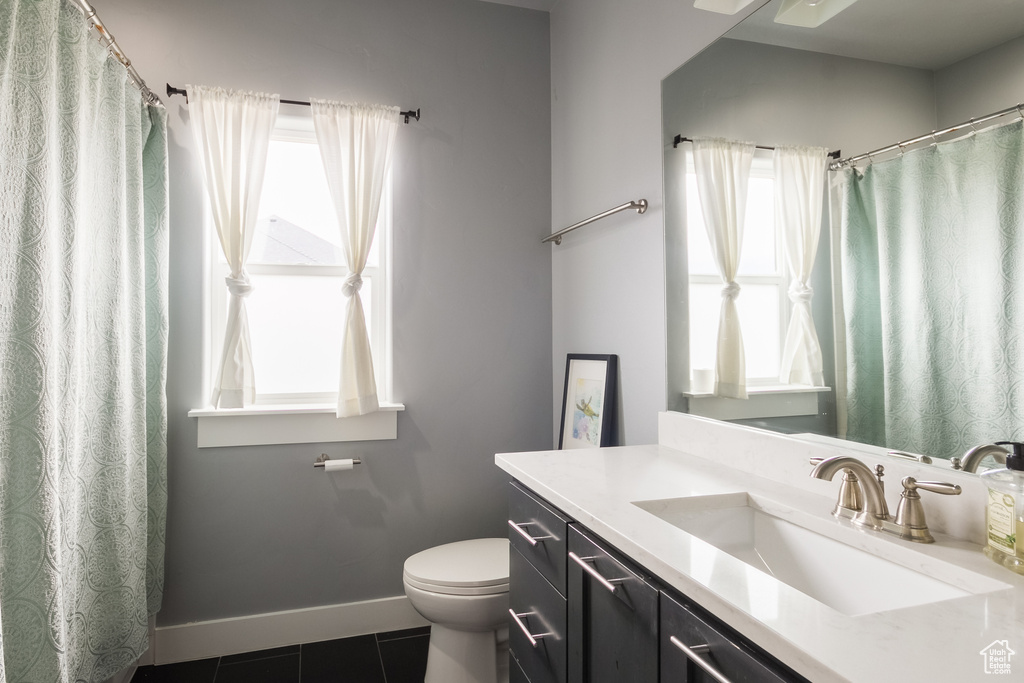 Bathroom featuring toilet, tile patterned floors, plenty of natural light, and baseboards