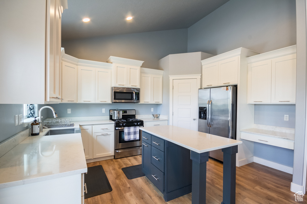Kitchen featuring a sink, white cabinetry, high vaulted ceiling, and stainless steel appliances