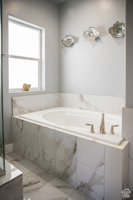 Full bath with a garden tub and marble finish floor