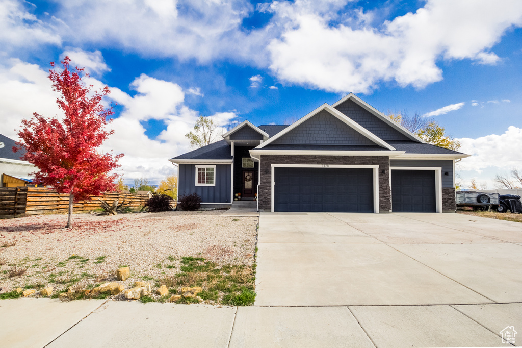 Craftsman-style house featuring a garage, fence, board and batten siding, and driveway