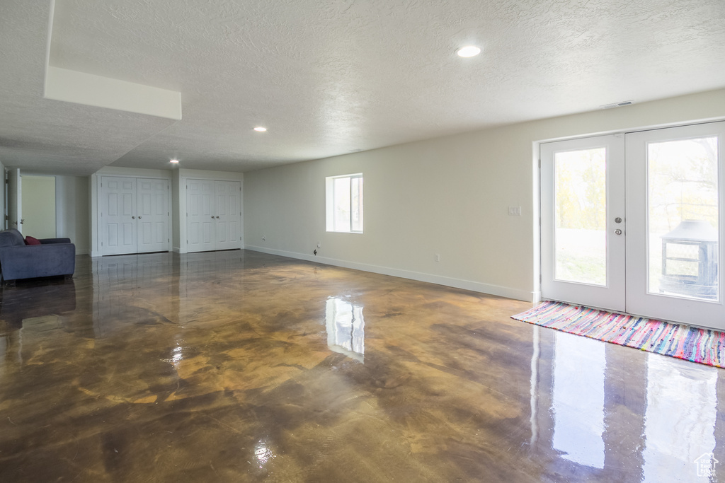 Below grade area with baseboards, french doors, and a textured ceiling