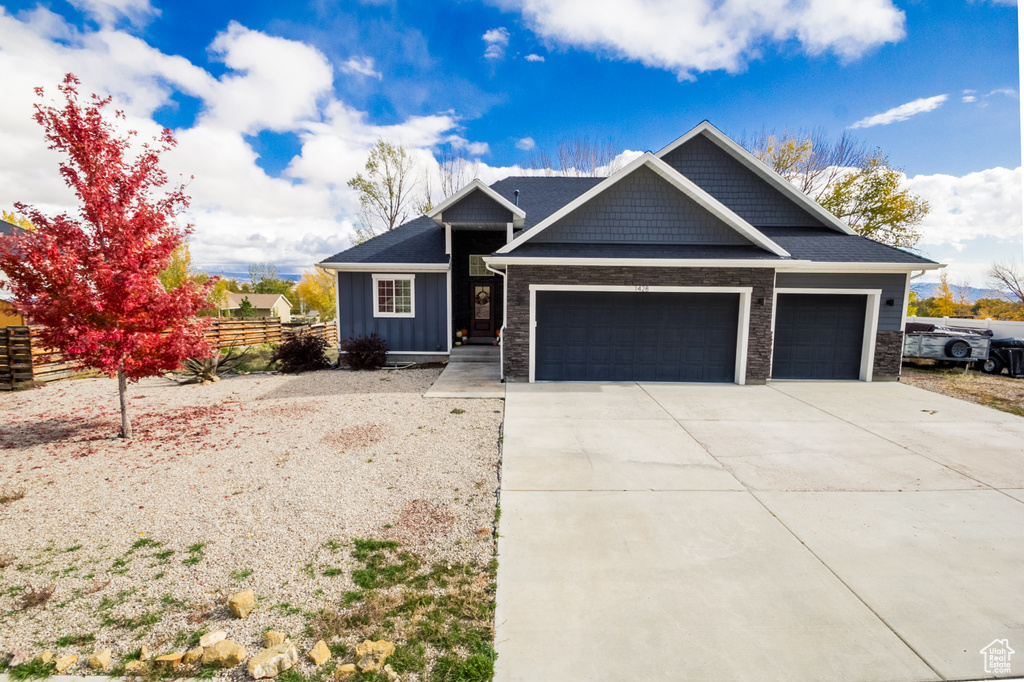 Craftsman-style house with board and batten siding, fence, driveway, and a garage