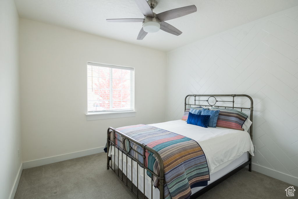 Carpeted bedroom with a ceiling fan and baseboards