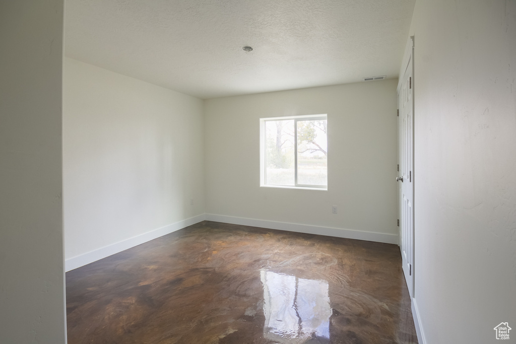 Spare room featuring baseboards, finished concrete floors, and visible vents