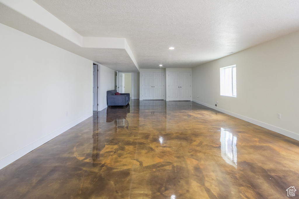 Unfurnished living room with baseboards, a textured ceiling, recessed lighting, and finished concrete floors