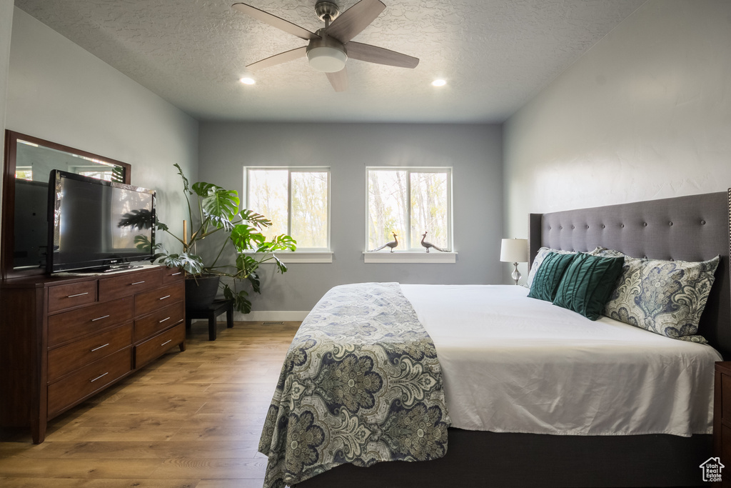 Bedroom with a textured ceiling, recessed lighting, baseboards, a ceiling fan, and wood finished floors