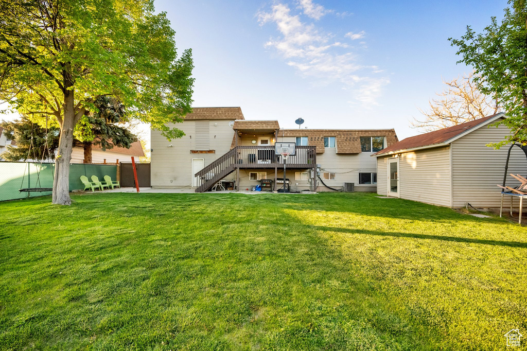 Rear view of property with fence, a deck, stairway, central air condition unit, and a yard
