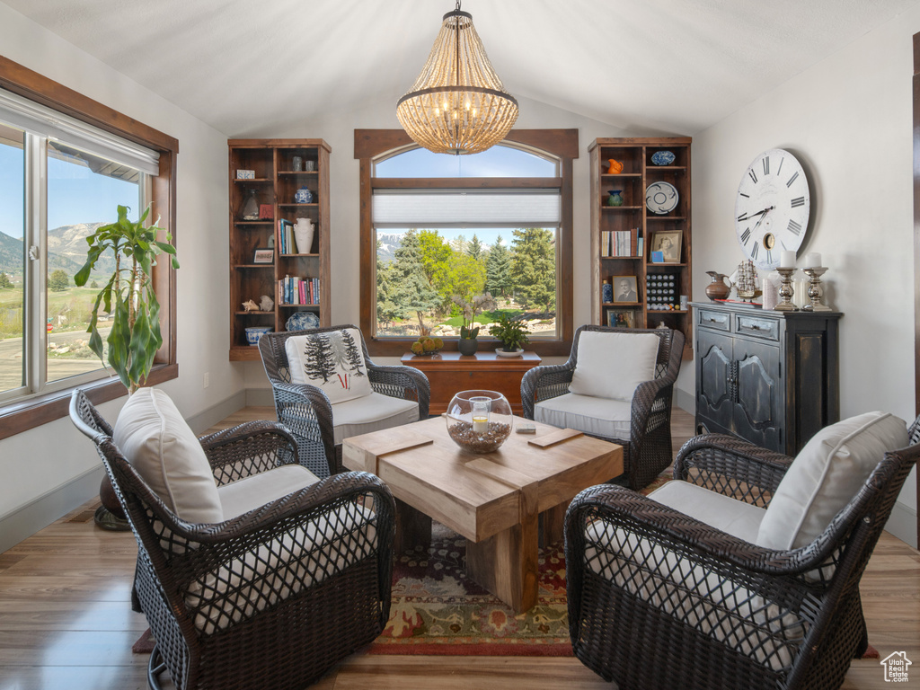 Living area featuring lofted ceiling, wood finished floors, and a notable chandelier