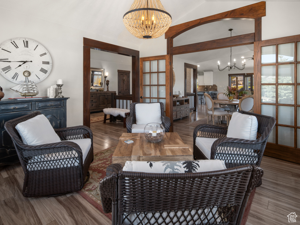 Living area with an inviting chandelier, wood finished floors, and high vaulted ceiling