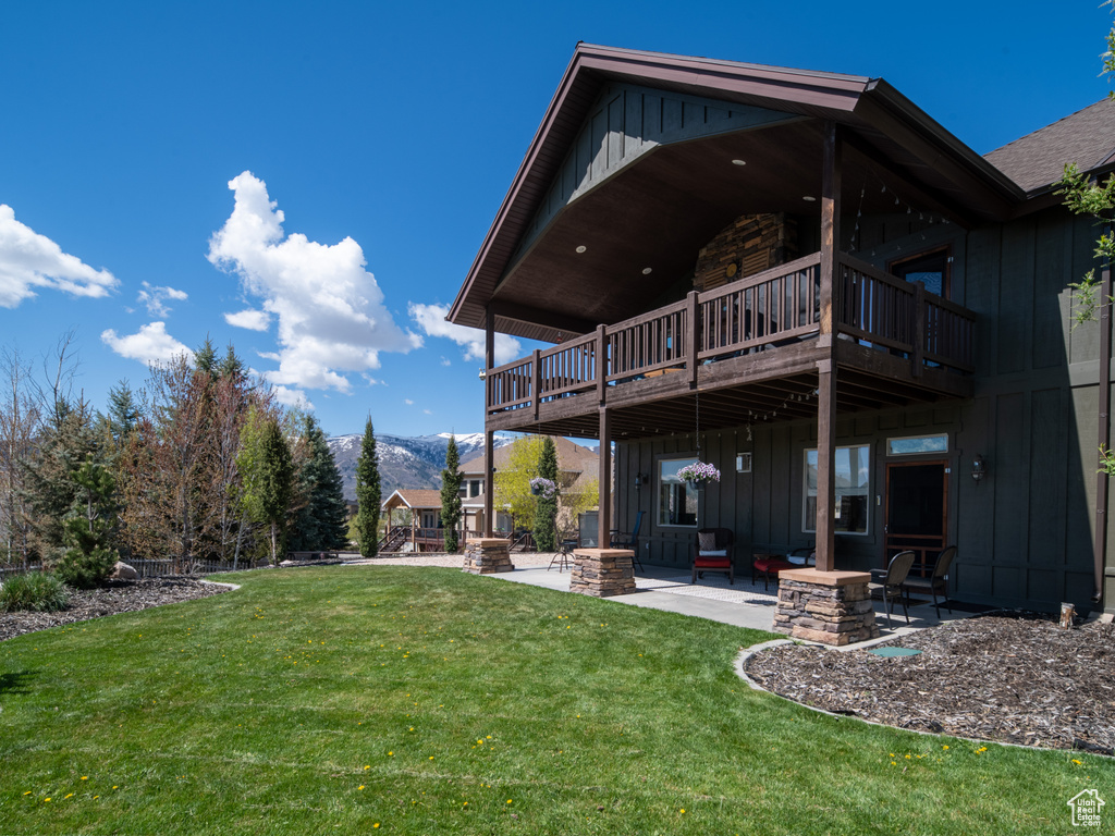 Rear view of property featuring a lawn, board and batten siding, a patio area, and a mountain view