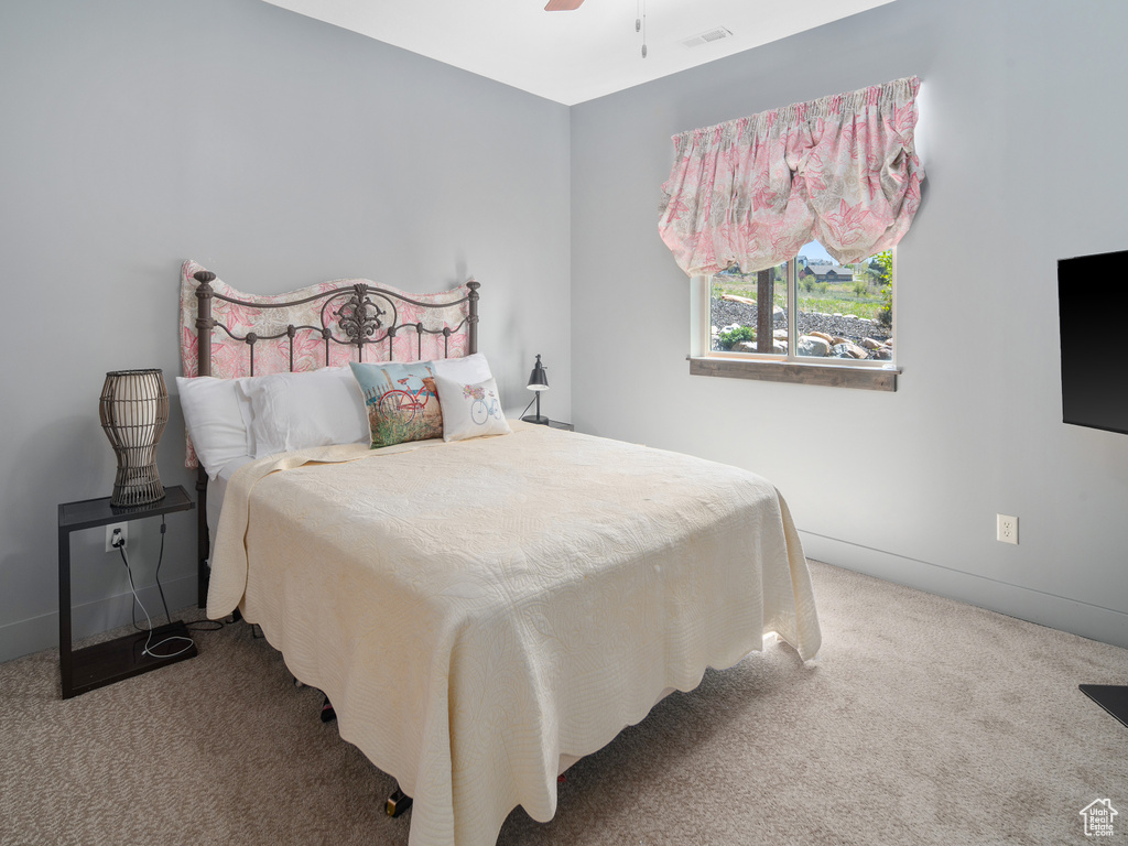 Carpeted bedroom with baseboards, ceiling fan, and visible vents