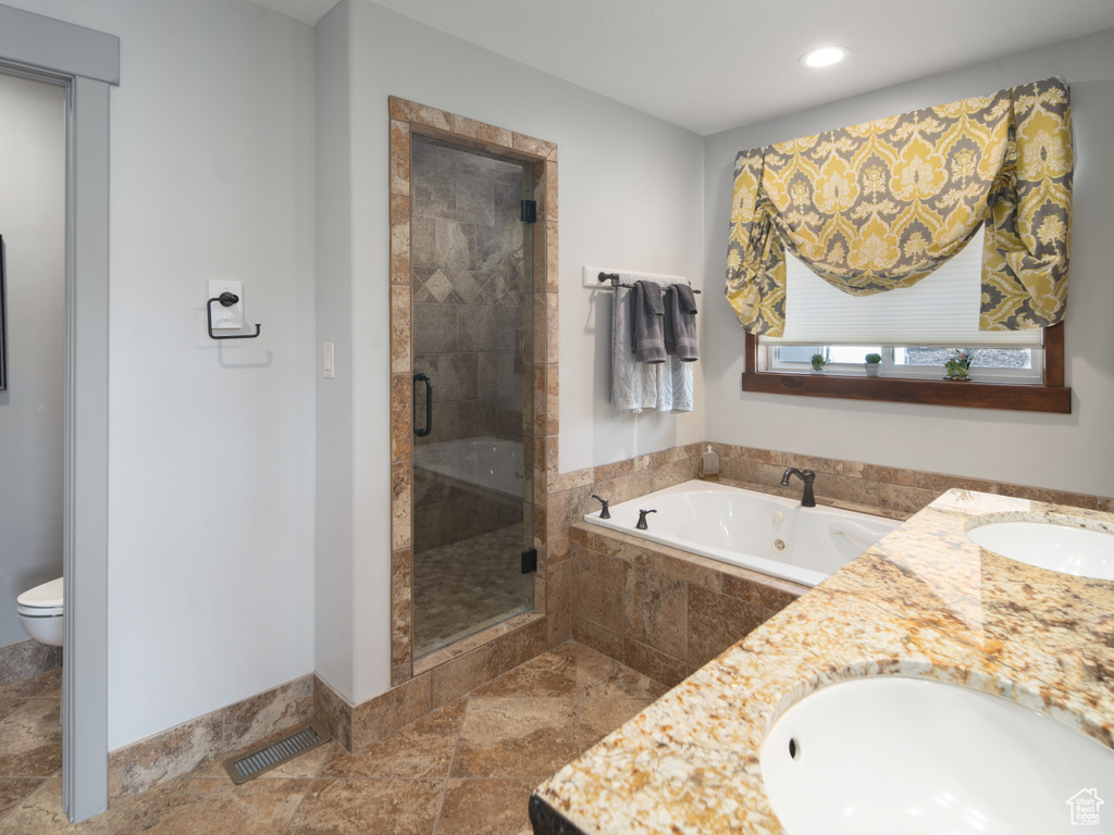 Bathroom featuring double vanity, visible vents, a stall shower, a tub with jets, and a sink