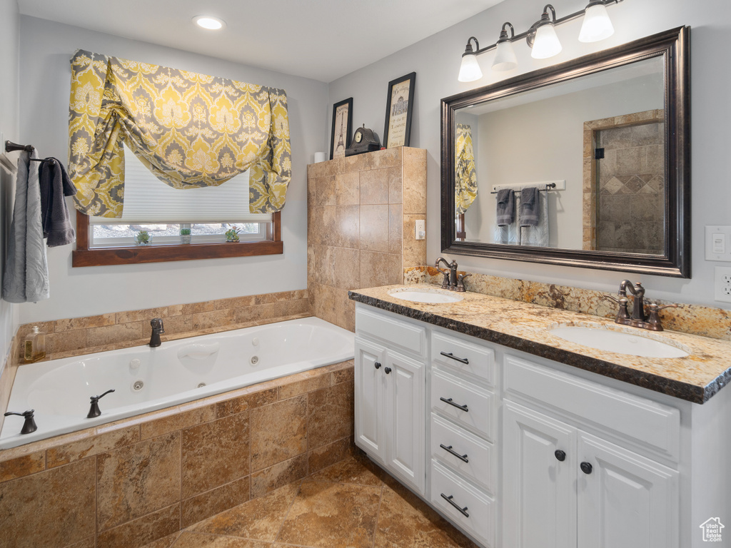 Bathroom featuring a sink, a jetted tub, recessed lighting, and double vanity
