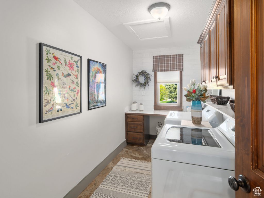 Laundry room featuring cabinet space, baseboards, washer and clothes dryer, and attic access