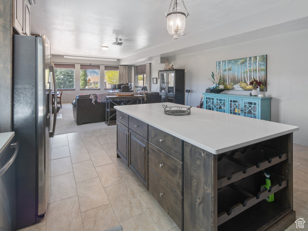 Kitchen featuring light countertops, open floor plan, dark brown cabinets, and stainless steel fridge with ice dispenser