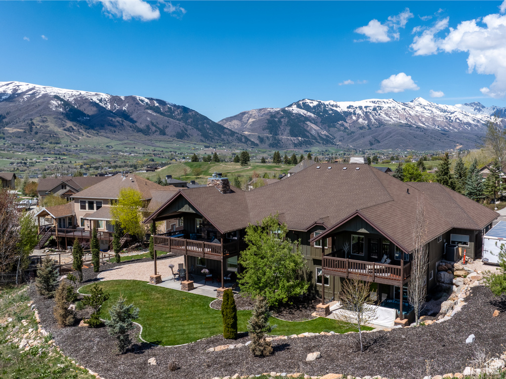 Exterior space with a lawn, a patio, a mountain view, and a balcony