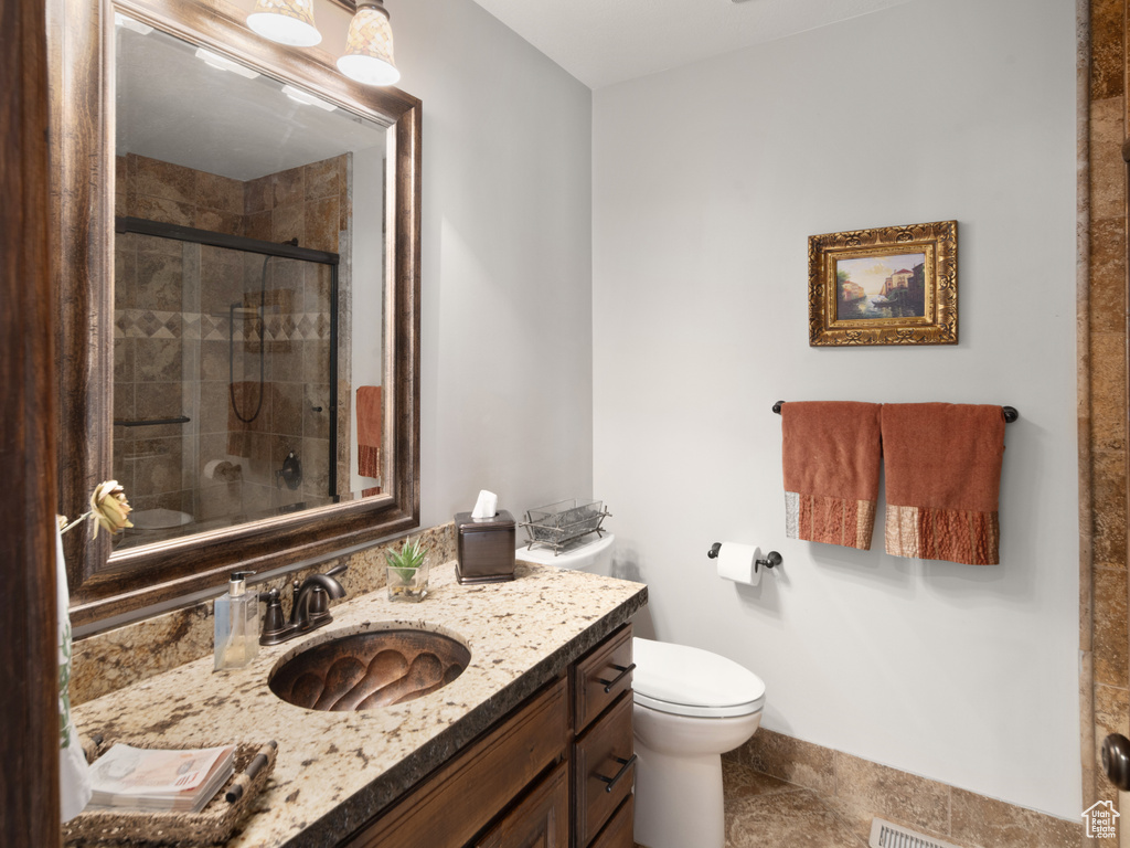 Bathroom featuring vanity, tile patterned flooring, a shower stall, and toilet
