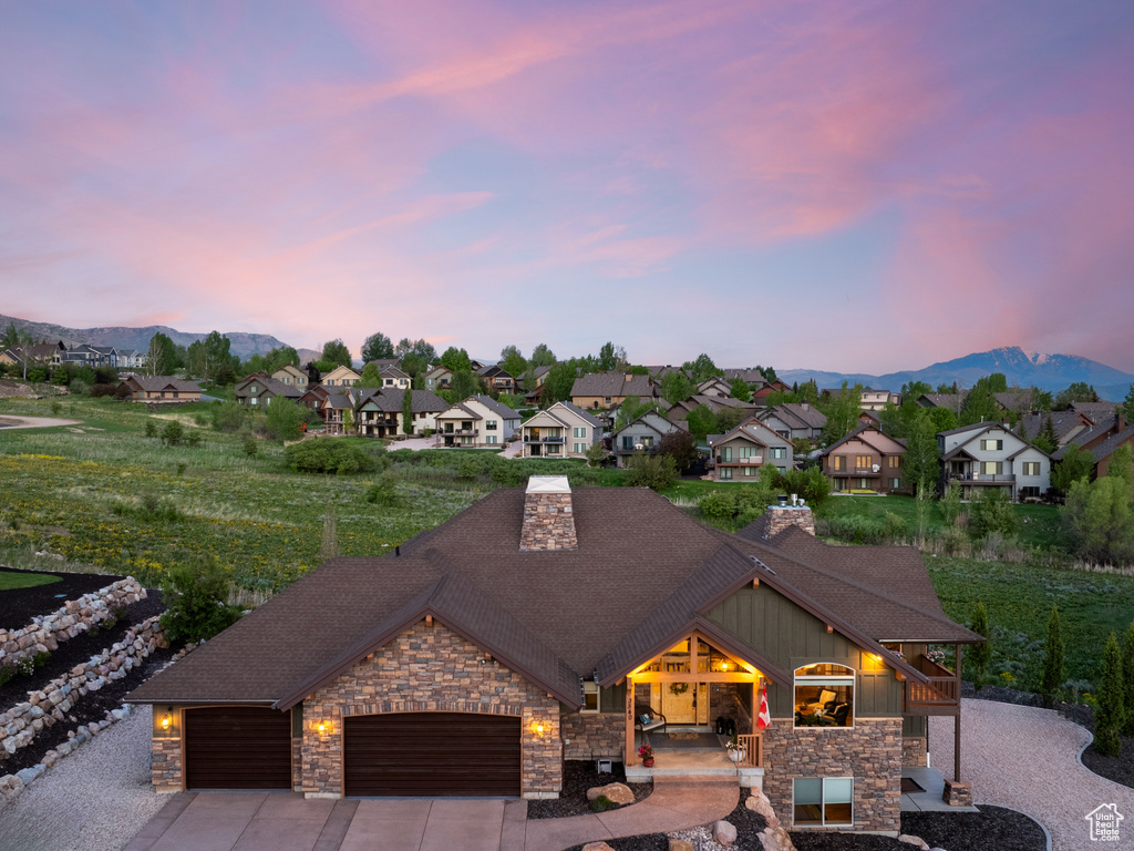 View of front of house with stone siding, an attached garage, and a residential view