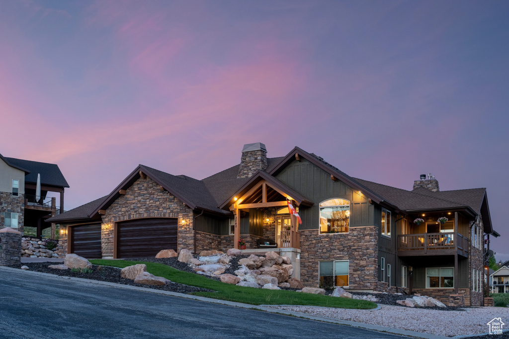 View of front of home featuring stone siding, a chimney, board and batten siding, and a balcony