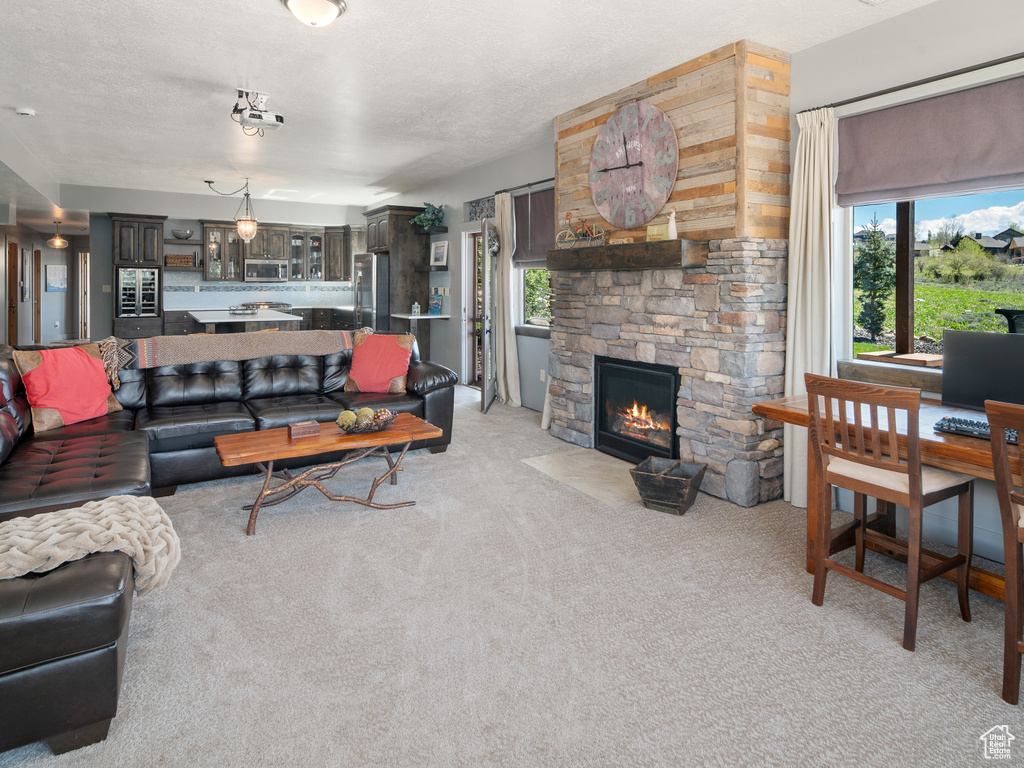 Living area featuring light colored carpet and a stone fireplace