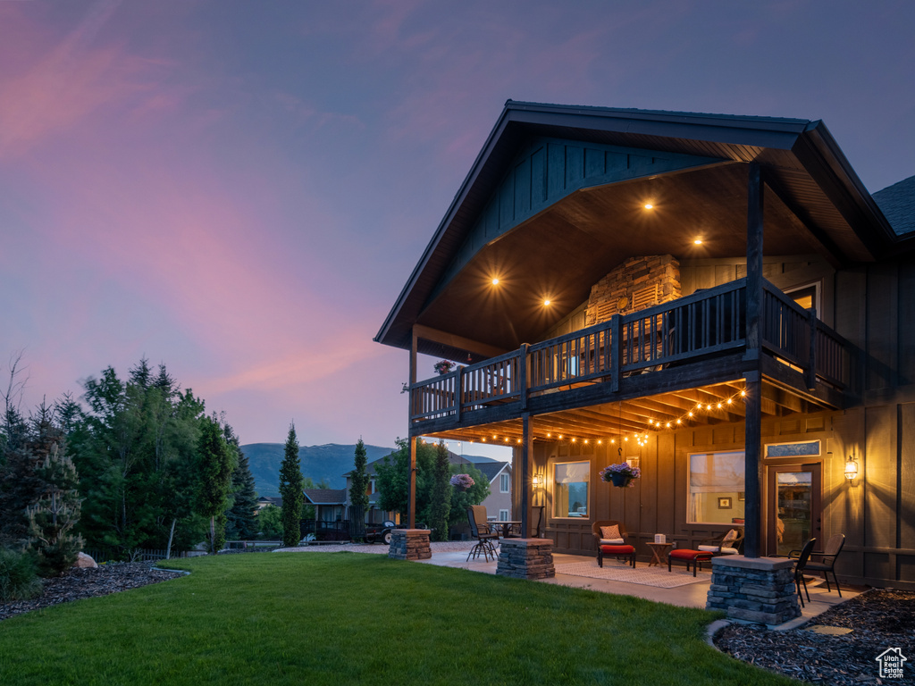 Back of house featuring board and batten siding, a patio area, a lawn, and an outdoor living space with a fire pit