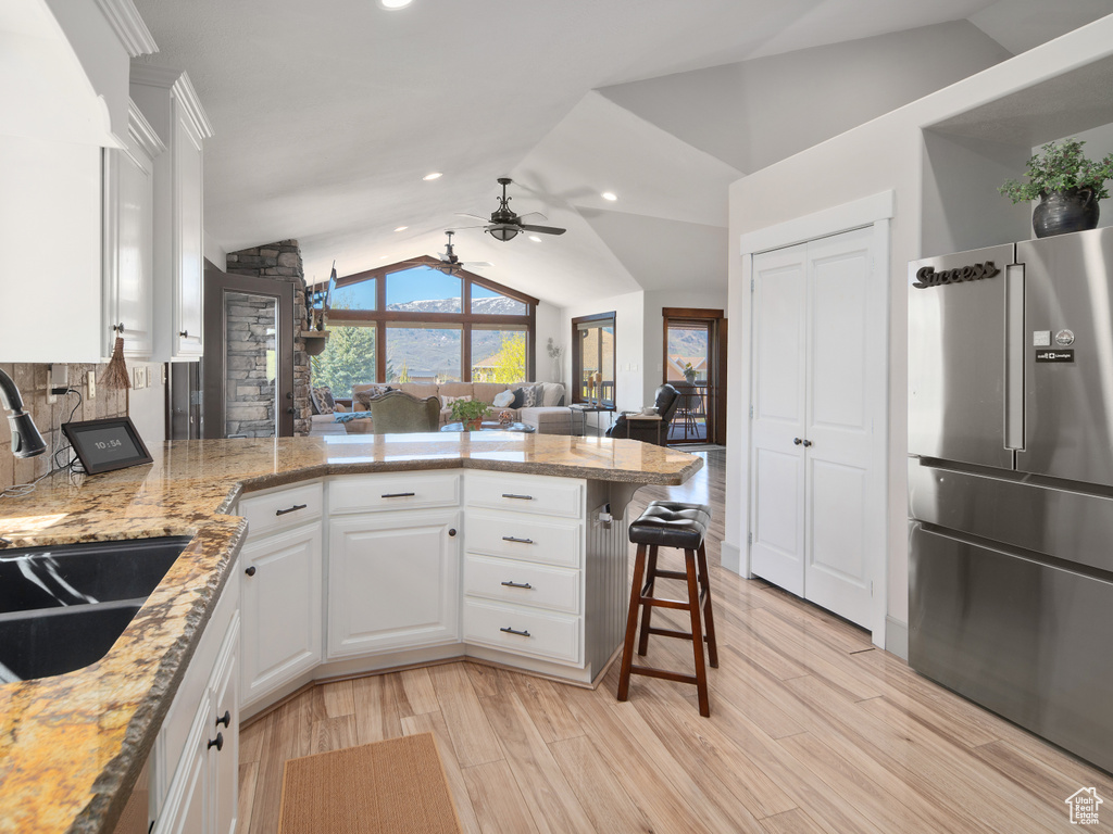Kitchen featuring white cabinets, ceiling fan, a peninsula, vaulted ceiling, and high quality fridge