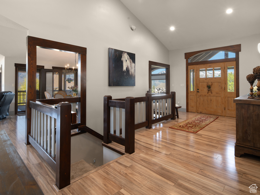 Entrance foyer featuring wood finished floors, high vaulted ceiling, baseboards, a chandelier, and recessed lighting