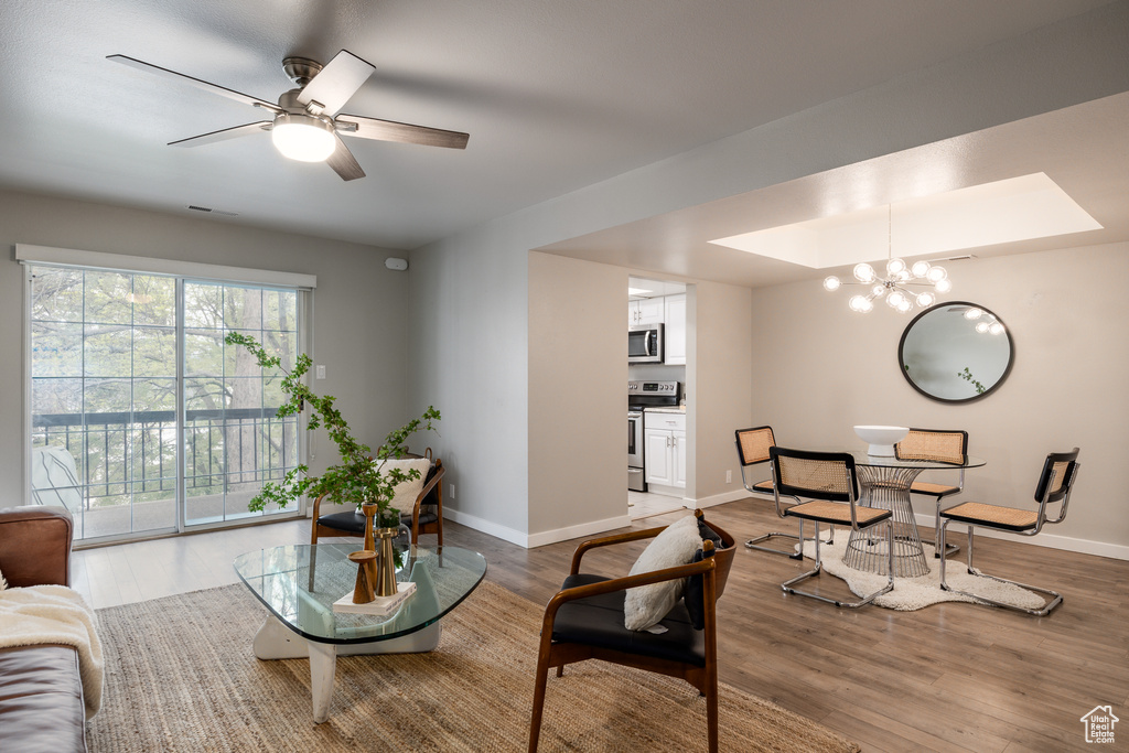 Living room featuring baseboards, ceiling fan with notable chandelier, wood finished floors, and visible vents