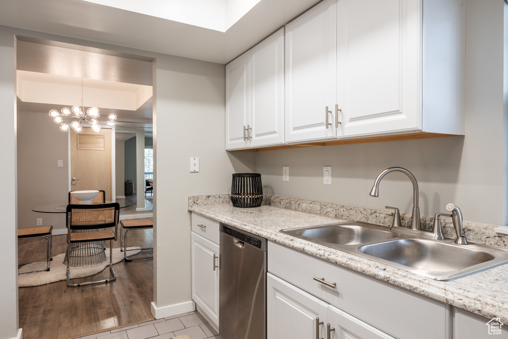 Kitchen with white cabinets, a notable chandelier, a sink, dishwasher, and light countertops