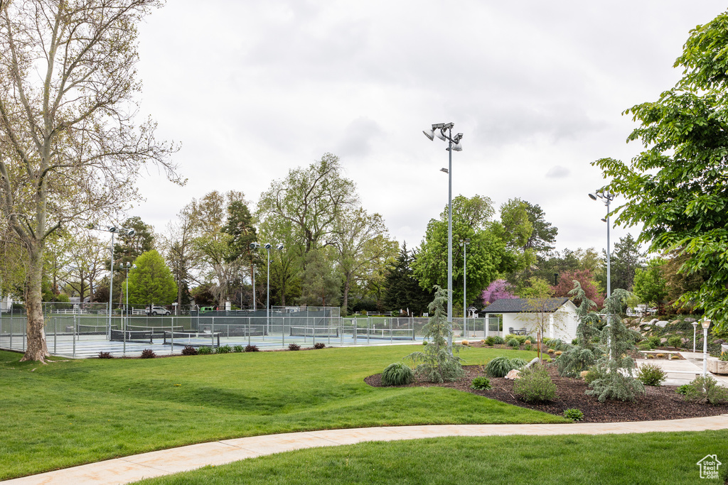 View of community featuring a lawn, a tennis court, and fence