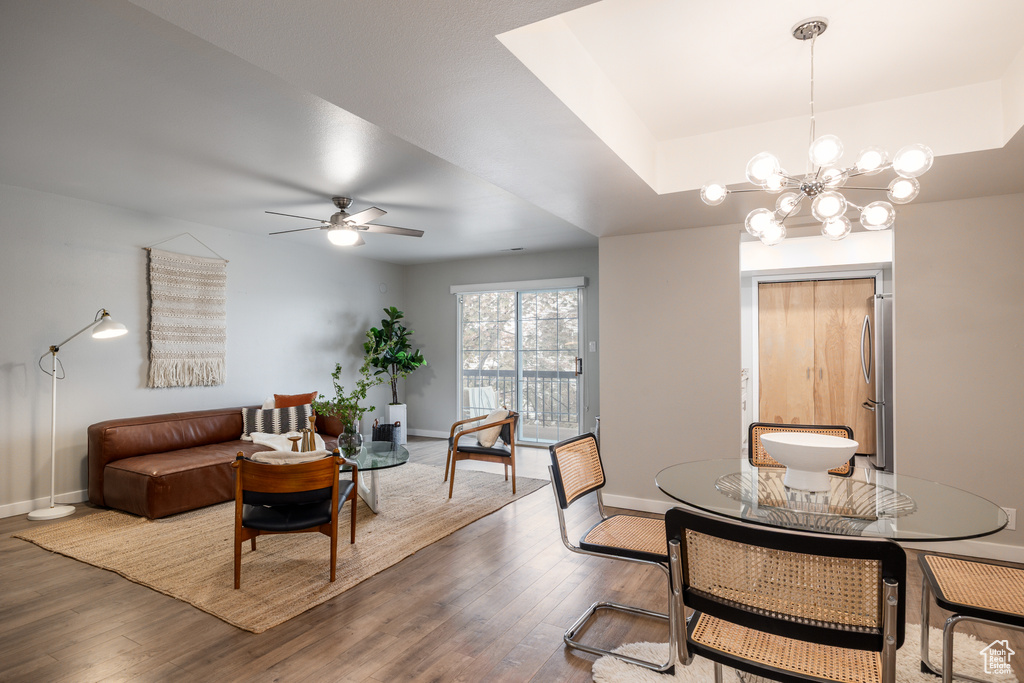 Dining area featuring baseboards, wood finished floors, and ceiling fan with notable chandelier