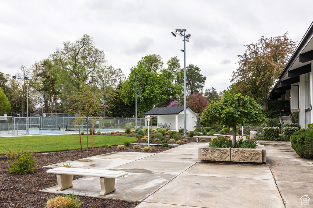Surrounding community with fence, an outdoor structure, a tennis court, and a patio area