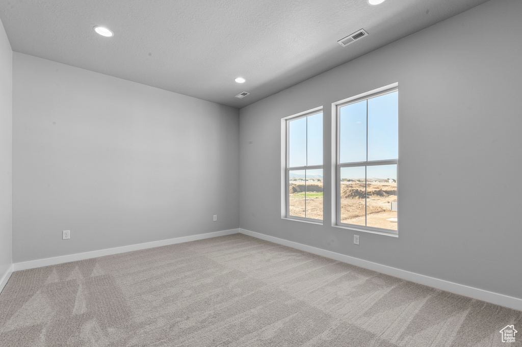 Empty room featuring baseboards, light carpet, recessed lighting, and visible vents