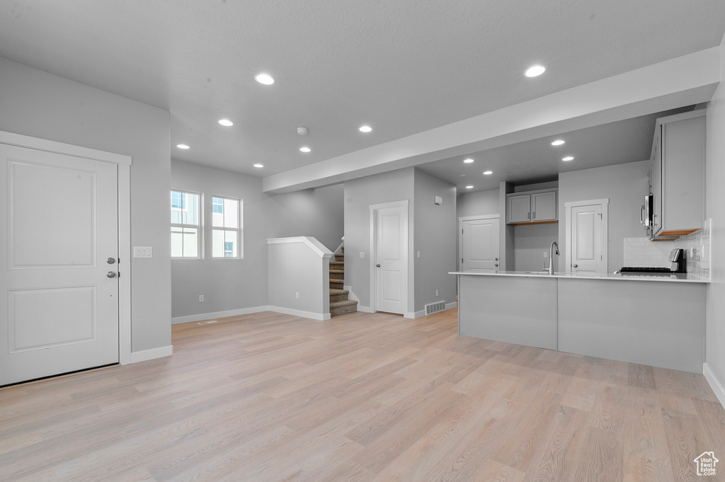Unfurnished living room with stairs, recessed lighting, baseboards, and visible vents