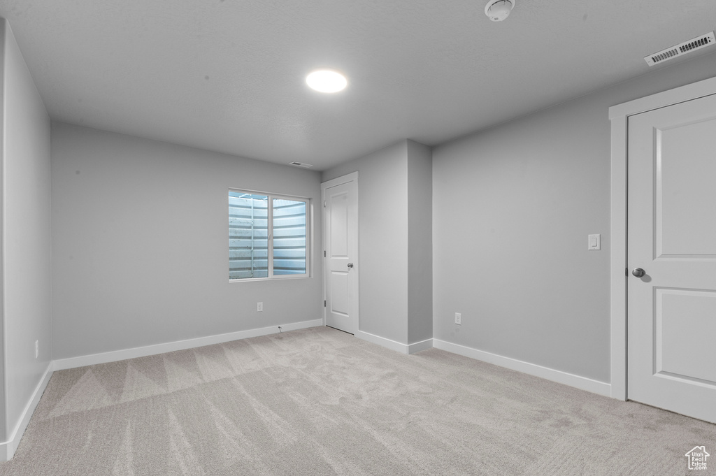 Empty room with visible vents, baseboards, and light carpet