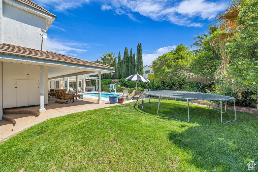 View of yard featuring a patio area, a trampoline, and an outdoor pool
