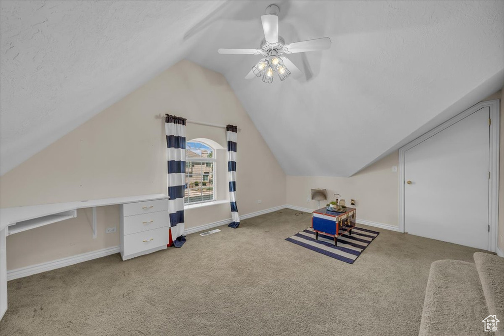 Additional living space with visible vents, baseboards, ceiling fan, carpet flooring, and vaulted ceiling