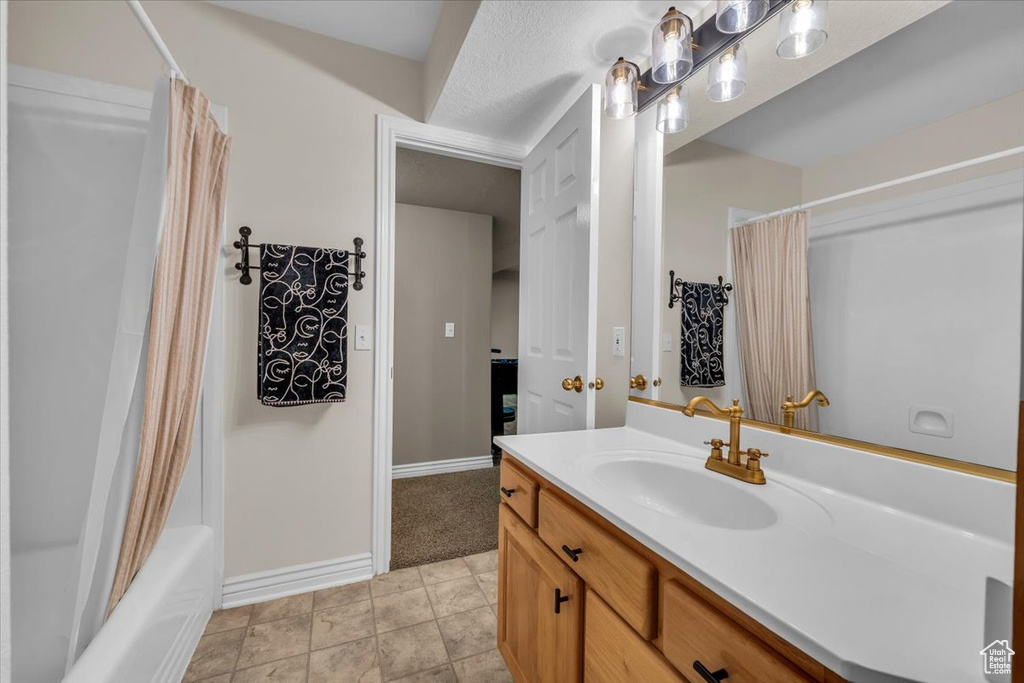 Full bath featuring baseboards, shower / bathtub combination with curtain, and vanity