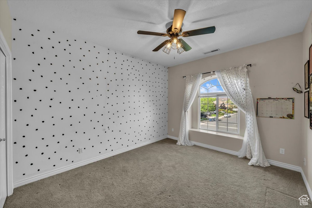 Carpeted empty room featuring a ceiling fan, baseboards, and visible vents