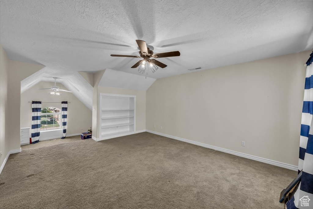 Interior space featuring a ceiling fan, a textured ceiling, visible vents, carpet floors, and baseboards