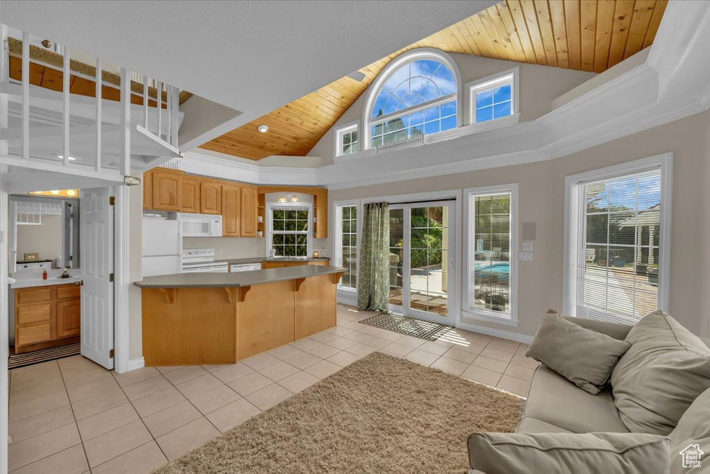 Kitchen featuring white appliances, open floor plan, a breakfast bar, and wood ceiling