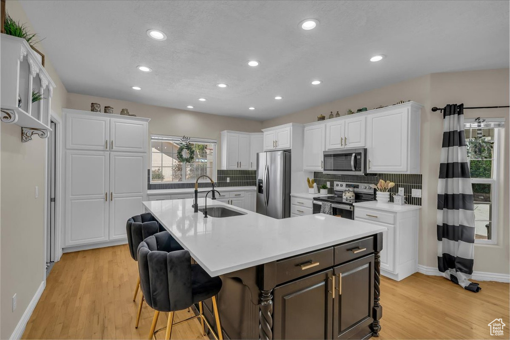 Kitchen featuring stainless steel appliances, baseboards, white cabinetry, and a sink