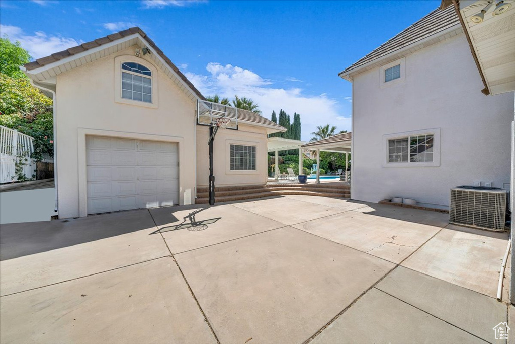 Exterior space with concrete driveway, a garage, cooling unit, and stucco siding