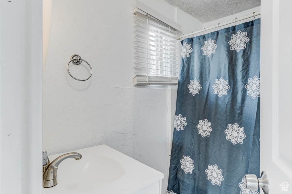 Bathroom with a sink, a shower with curtain, and a textured ceiling