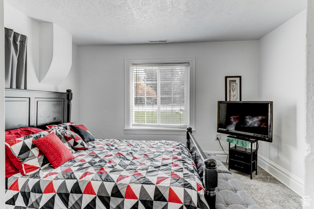 Bedroom with baseboards, carpet flooring, a textured ceiling, and visible vents