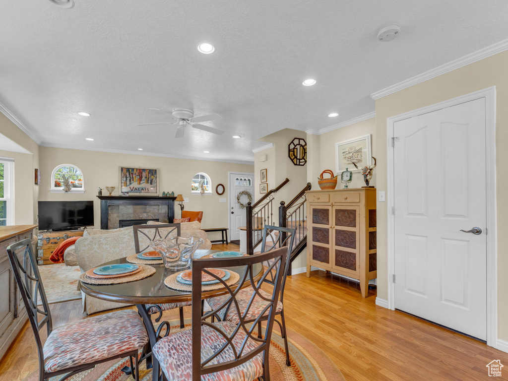 Dining area featuring ornamental molding, stairs, a fireplace, recessed lighting, and light wood finished floors