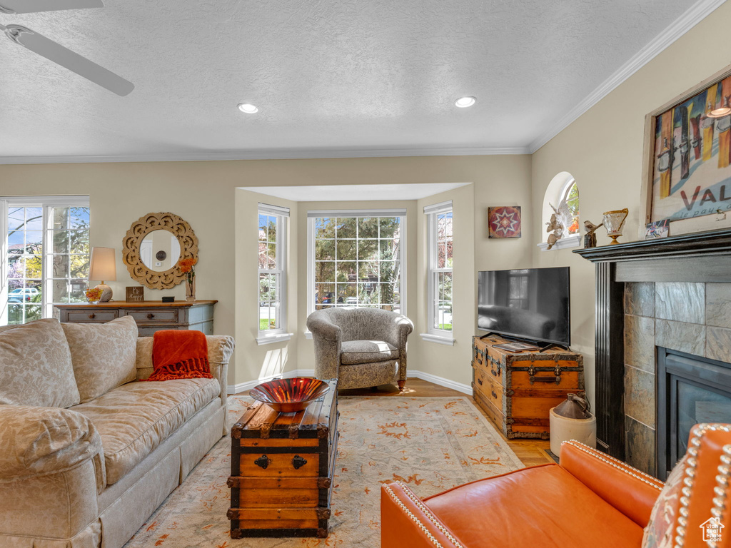 Living area with baseboards, light wood-type flooring, a textured ceiling, and a tile fireplace